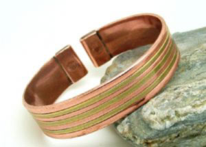Brass lines press into a plain copper band. Each end is fitted with rare earth magnets